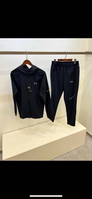 Svart träningsset från Under Armour - Säljer ett svart träningsset från Under Armour med zip hoodie och matchande byxor. Setet har diskreta loggor på bröstet och benet, samt dragkedja på jackan. Perfekt för gymmet eller löprundan. Materialet är lätt och andas.