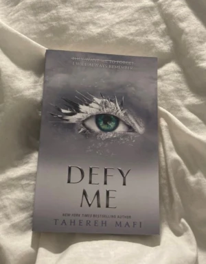 Defy Me - En bok med ett mystiskt omslag som visar ett öga omgivet av is eller kristaller. Perfekt för dig som gillar spännande och känsloladdade berättelser. Skriven av New York Times-bestsäljande författaren Tahereh Mafi, passar den dig som söker något unikt och fängslande.