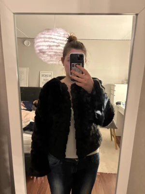 Svart pälsjacka från Lefties - Säljer en svart fluffig pälsjacka från Lefties Outerwear Collection. Jackan har lång ärm, är croppad och har en riktigt mjuk och gosig känsla. Perfekt för dig som vill ha en cool och trendig look med extra volym. Fodrad insida för extra komfort.