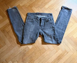 Grå jeans från Crocker - Snygga grå Crocker med slim fit och klassisk femficksdesign. Jeansen har en mörkgrå tvätt, raka ben och råa, slitna benslut för en cool vibe. Materialet är mjukt jeans i bomull med lite stretch för extra komfort.