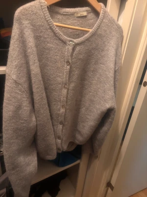 Grå kofta från Gina Tricot XL - Mysig grå kofta från Gina Tricot i storlek XL. Koftan är stickad med rund halsringning och knappar framtill. Perfekt för lager-på-lager och har en enkel, clean look som funkar till allt. Materialet känns mjukt och skönt mot huden.