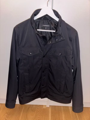 J.Lindeberg Bailey Poly Jacka  - Säljer en snygg stilren J.Lindeberg jacka då den inte kommer till användning. Nypris ca 3.400kr Säljer för 1000 Obs finns en enda defekt vilket är logan (se bild 3) rätt så osynlig men finns. Kan tänka mig att gå ned i pris vid smidig affär!