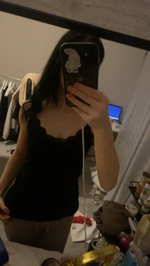 Svart linnetopp med spetskant - Säljer en svart linnetopp med snygg spetskant runt halsringningen. Toppen är ärmlös och har en feminin, lite loose passform. Perfekt att styla med smycken eller under en jacka. Materialet känns mjukt och lätt mot huden.