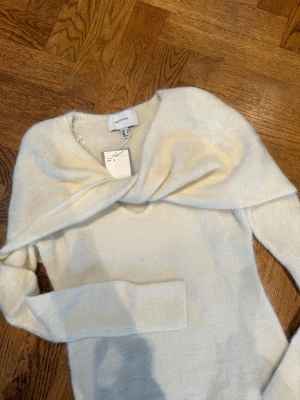 Ljusbeige omlottstickad tröja H&M - Supersnygg ljusbeige stickad tröja från H&M Edition med omlottdetalj över axlarna och v-ringad hals. Mjuk och skön känsla, perfekt för att ge din outfit en clean och chill vibe. Långärmad och i en slim passform som sitter snyggt.