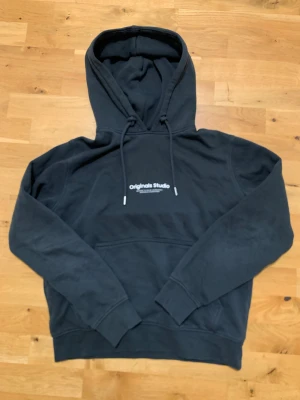 Mörkgrön hoodie från Jack & Jones - Mörkgrön baggy hoodie från Jack & Jones med känguru ficka och avtagbara snören. Den är i bra skick och har inga skador som jag har sätt men jag kan kika närmare vid seriöst intresse. Den har en mjuk insida (se bild) perfekt nu på vintern. Pris kan diskuteras och Hör av dig vid funderingar!