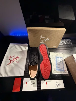 Christian Louboutin svarta  - Svarta sneakers från Christian Louboutin med ikonisk röd sula och broderad logga på hälen. Skorna har snörning, platt sula och är tillverkade i lyxig mocka med skinnfoder. Snygg, chunky design med exklusiva detaljer och medföljande dustbag och box. Helt nyan och oanvända! Pris kan diskuteras. 