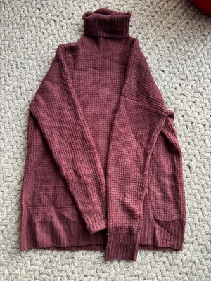 Vinröd polotröja Linn Ahlborg x NA-KD - Säljer en vinröd polotröja från Linn Ahlborg x NA-KD i storlek S. Tröjan är stickad med ribbad polokrage och har ett grovt rutigt mönster. Långärmad och loose fit, perfekt för kyliga dagar. Supermysig och trendig färg som lyfter din höst- och vinterstil.