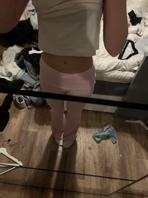 Ljusrosa bootcut yogapants/mjukisbyxor - Säljer ett par ljusrosa yogapants/mjukisbyxor med bootcut passform och mid midja. Byxorna är stretchiga och sitter snyggt över höfterna, med utsvängda ben. Perfekta för chill dagar och riktigt sköna att ha på sig.