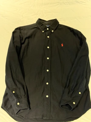 Polo Ralph Lauren skjorta - Svart Ralph Lauren skjorta i storlek S. Den är i bra skick och har endast används få antal gånger. Perfekt för dig som söker en ny finskjorta🤩