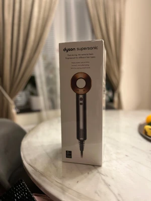 Dyson Supersonic - Dyson Supersonic hårfön med avancerad digital motor och Air Amplifier-teknik för snabb torkning utan extrem värme. Inkluderar fem magnetiska stylingmunstycken för olika hårtyper. Produkten är ny i oöppnad förpackning, perfekt för skonsam och effektiv hårvård.