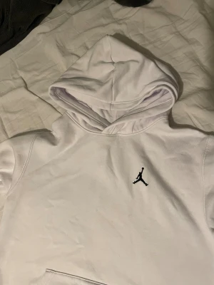Vit Jordan hoodie  - Säljer en clean vit hoodie från Jordan med klassisk svart Jumpman-logga på bröstet. Tröjan har huva, magficka och långa ärmar. Perfekt för dig som gillar sportig och stilren streetwear. Skicka ett prisförslag om det inte passar dig