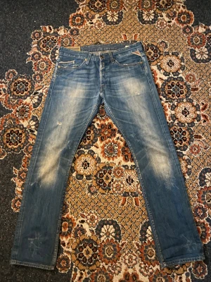 Replay jeans blå straight fit 32/32 - Säljer ett par snygga Replay jeans i klassisk blå tvätt med slitningar och faded detaljer. Modellen har rak passform. Skicket är bra.