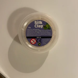 Silk Clay 14g - Silk Clay är en lätt, självhärdande modellera med mjuk och flexibel konsistens. Perfekt för pyssel och modellering. Förpackningen innehåller 14g vit lera, och den är i gott skick med lite användning. Passar både barn och vuxna, CE-märkt och säker för kreativt skapande.
