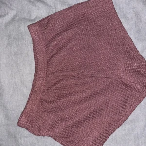 Ljuslila strukturerade shorts i S - Säljer ett par ljuslila shorts med snyggt strukturerat tyg. De har elastisk midja och är tillverkade i mjuk polyesterblandning med lite stretch för extra komfort. Perfekta för varma dagar när du vill ha något bekvämt men ändå stilrent.