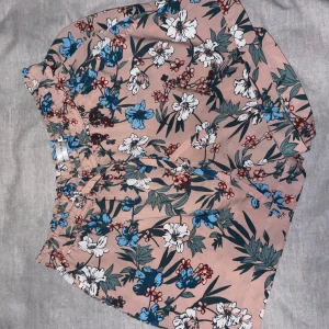 Blommiga shorts från Angelology XS - Säljer ett par superfina shorts från Angelology i storlek XS. De är ljusrosa med blommigt mönster i vitt, blått och grönt. Shortsen har elastisk midja och är tillverkade i ett mjukt, lätt material som passar perfekt till sommaren.