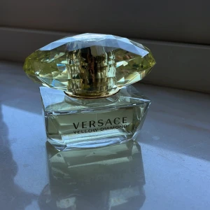 Versace Yellow Diamond Eau de Toilette 50ml - Versace Yellow Diamond är en lyxig parfym i en elegant glasflaska med en stor, facetterad gul kork som liknar en diamant. Flaskan rymmer 50 ml och har Versaces klassiska Medusa-symbol på korken. Doften är fräsch och feminin. 