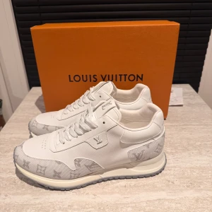 Louis Vuitton Run Away sneakers vita - Säljer ett par Louis Vuitton Run Away sneakers i vitt skinn och textil med klassiskt LV-monogram i grått på tå och häl. Snygg och stilren design med rund tå, snörning och robust sula. Perfekta för dig som vill ha lyxiga och trendiga sneakers.