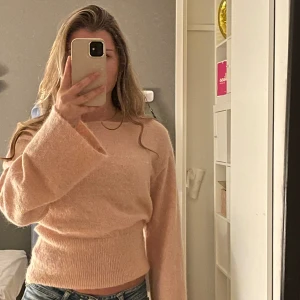 Ljusrosa tröja med vida ärmar - Mysig ljusrosa tröja med breda, långa ärmar och tajtare midja. Tröjan har en fluffig, mjuk yta och en avslappnad passform som ger en trendig look. Perfekt för dig som gillar en enkel men ändå stylish stil.