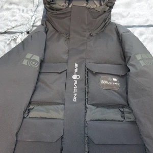 Sail racing jacka - Grym svart dunjacka från Sail Racing med Gore-Tex Infinium, stora fickor och huva med logga. Jackan har quiltad baksida, 700 fill power dun och coola detaljer som Sail Antarctica-märke och dragkedja. Perfekt för kalla vinterdagar och riktigt snygg streetstil. Priset kan diskuteras. Nytt pris 6400