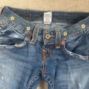 Blå bootcut jeans från True Religion - Säljer ett par blå jeans från True Religion med bootcut passform och slitna detaljer. sitter skit snyggt!! 💕