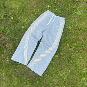 Grå Archive mjukisbyxor med ränder - Grå mjukisbyxor från Archive med breda ben och vita ränder längs sidorna. Byxorna har elastisk midja med vit snörning och är tillverkade i mjukt bomullsmaterial. Fråga gärna för mått och andra misc saker😊