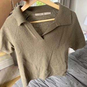Beige stickad polotopp från Cotta Mari - Säljer en beige stickad polotopp från Cotta Mari i storlek XS. Toppen har korta ärmar, krage och v-ringad hals. Den är croppad och har en mjuk, ribbad kant vid ärmslut och nederkant. Perfekt för dig som gillar chill och stilren look.