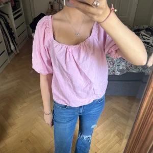 Ljusrosa blus med puffärm - Säljer en ljusrosa blus med puffiga korta ärmar och söt broderad struktur. Blusen har en fyrkantig halsringning och är lätt croppad i modellen. Perfekt för dig som gillar romantiska och feminina detaljer. Superfin att styla med jeans eller kjol!