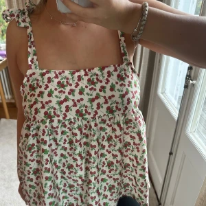 Knyttopp med korsbär - Säljer denna underbara sommartoppen med körsbärsmönster. Så unik och söt! Uppskattad storlek M, med justerbara band. 