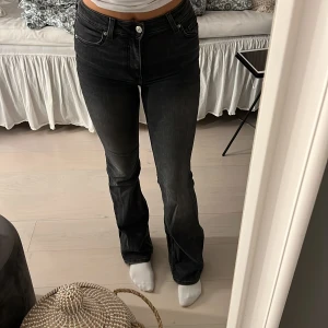 Svarta bootcut jeans - Snygga svarta jeans med bootcut-modell och hög midja. Jeansen har klassisk femficksdesign och subtila slitningar för en cool look. Perfekta för dig som gillar en tidlös stil med lite edge.