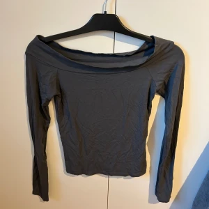 Grå offshoulder topp från BikBok - Säljer en stilren grå offshoulder topp från BikBok i storlek S. Toppen har lång ärm och en bred, nedvikt halsringning som ger en snygg och modern look. Materialet är mjukt och stretchigt, perfekt för att matcha med jeans eller kjol. Tröjan är i ett bra skick!