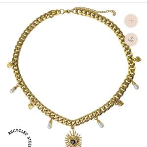 Jättefint halsband från WOS - Chunky guldhalsband med kedja, dekorerat med små hjärtan och droppformade pärlor. I mitten hänger en solformad berlock med svart hjärta. Perfekt statement-piece för dig som vill sticka ut.