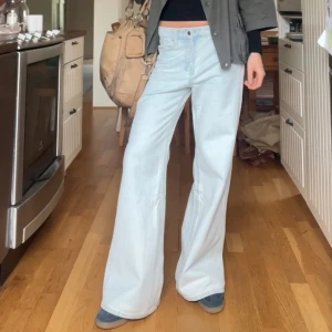 Ljusblå wide jeans - Säljer ett par ljusblå jeans med riktigt breda ben och medelhög midja. Jeansen har klassisk femficksdesign och stängs med knapp och dragkedja. Perfekta för dig som gillar en avslappnad och trendig look. Lite bootcut i de me!