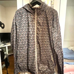 Windbreaker från Guess - Säljer en oanvänd vändbar vindjacka från Guess med huva och dragkedja. Ena sidan är beige med Guess-logga på bröstet, andra sidan har ett grafiskt mönster i svart, beige och vitt. Storlek Xl men sitter som en L och vid snabb affär kan priset diskuteras😊