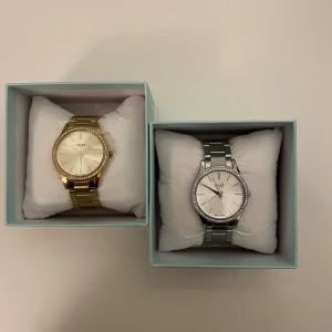 Två Regal armbandsur i guld och silver - Säljer två stilrena armbandsur från Regal, ett i guld och ett i silver. Båda har rund urtavla med diskreta stenar runt kanten och metallarmband. Perfekta accessoarer för att lyfta din outfit. Och för endast 199kr!!