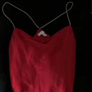 Röd blus med tunna axelband - Säljer en snygg röd silkes blus med tunna axelband och enkel, stilren. Passar dig som gillar plagg med en festlig touch.