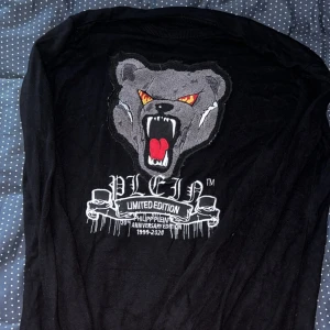 Svart tröja från Philipp Plein med björn - Svart långärmad tröja från Philipp Plein Limited Edition med stor broderad björn och text på ryggen. Tröjan har ribbade muddar och är i mjukt material, perfekt för dig som gillar statement-plagg och unika detaljer.