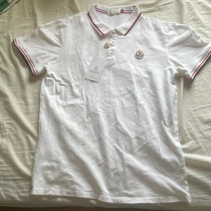 Vit Moncler pikétröja med röd detalj - Vit pikétröja från Moncler storlek M. Ny med prislapp. Pris kan diskuteras vid snabb affär 