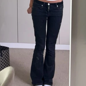 Svarta bootcut jeans - Snygga svarta jeans med slitningar som man ser på sista bilden med bootcut-modell och klassisk femficksdesign. Byxorna har låg midja och är tillverkade i ett stretchigt jeanstyg som sitter skönt. Perfekta för dig som gillar en tidlös och trendig look.