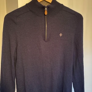 Mörkblå merinoullströja Morris M - Säljer en mörkblå stickad tröja från Morris i 100% merinoull. Tröjan har half zip med läderdetalj, hög krage och broderad logga på bröstet. Perfekt för lager-på-lager och snygg till jeans eller chinos. Passar nog också storlek S