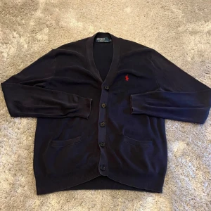 Cardigan från Polo Ralph Lauren - Mörkblå cardigan från Polo Ralph Lauren i storlek S. Den är använd men har definitivt mer att ge. Hör gärna av er vid funderingar!