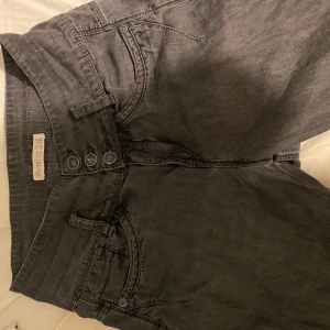 Svarta wide jeans från Denim86 - Säljer ett par svarta jeans från Denim86 med bred passform och hög midja. Byxorna har flera dekorativa sömmar, tre knappar framtill och klassiska fickor både fram och bak. Materialet är jeans och färgen är en mörk tvättad svart.(lite slitna längst ner visar på sista bilden)