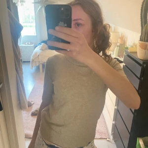 Beige stickad polotröja från Zara - Säljer en beige stickad polotröja från Zara med korta ärmar och ribbade detaljer vid ärmslut, krage och nederkant. Tröjan har en mjuk och skön känsla och passar perfekt till både jeans och kjol. Enkel och stilren design.