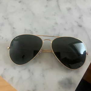 Ray-Ban aviator solglasögon guld - Säljer ett par klassiska Ray-Ban aviator solglasögon med guldfärgad metallram och mörka svarta linser.