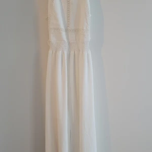 Vit långklänning från Misscix - Supersnygg vit långklänning från Misscix med omlott och knyt i ryggen. Klänningen har smock i midjan, broderade detaljer framtill och är ärmlös. Materialet är mjukt och lätt, perfekt för varma dagar. Stilren och fräsch look som verkligen sticker ut.