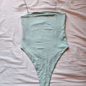 Ljusgrön body med smala axelband - Säljer en stilren ljusgrön bikini med högt skuren underdel och tunna axelband. Pga att jag fick den och den är för stor. Enkel och modern design som ger en clean look på stranden. Perfekt för dig som gillar minimalistiska badkläder.