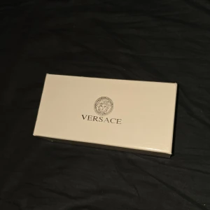 Svarta Versace solglasögon med gulddetaljer - Exklusiva svarta solglasögon från Versace med snygga guldfärgade detaljer och Medusa-emblem på sidorna. Glasögonen har en klassisk aviatorform och levereras i originaletui med certifikat. Perfekt accessoar för dig som vill sticka ut med lyxig stil.