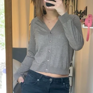 Brun kofta, Massimo Dutti - Säljer en brun kofta från Massimo Dutti med v-ringning och knappar framtill. Koftan är i en mjuk ull- och viskosblandning, har lång ärm och en lite croppad passform. Perfekt att slänga över ett linne eller t-shirt. Använd enstaka gånger 