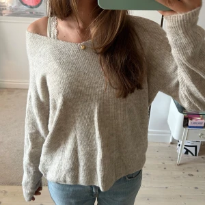 Beige ribbad stickad tröja Vero Moda - Mysig beige stickad tröja från Vero Moda med v-ringning och ribbad struktur. Tröjan har en loose passform och långa ärmar, perfekt för lager-på-lager. 