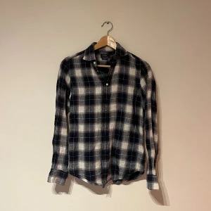 Rutig skjorta från Polo Ralph Lauren - Snygg rutig skjorta från Polo Ralph Lauren i klassisk passform. Skjortan är blå och vit med knappar framtill och broderad logga på bröstet. Perfekt för dig som gillar en avslappnad men stilren look. Skjortan sitter slim fit