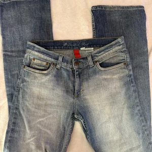 Blå jeans med broderade bakfickor - Snygga blå jeans från Divided Red i tvättad denim med coola gulbroderade vågmönster på bakfickorna. Klassisk femficksmodell med normal passform och raka ben. Perfekta för dig som gillar en avslappnad stil med lite edge.
